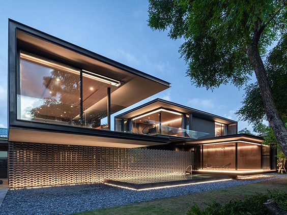 Modern luxury house with extensive glass windows and integrated exterior lighting, representing high-end residential electrical installations